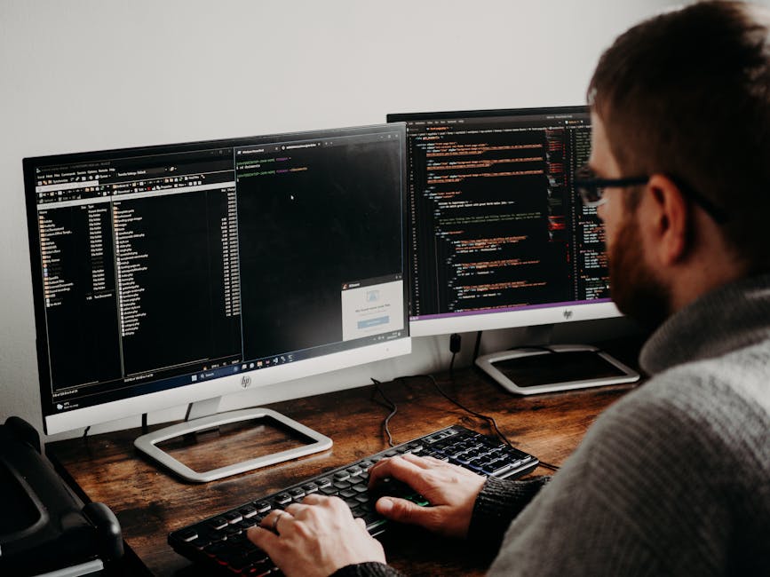 The image displays a computer screen with a dark background showing lines of colourful code and programming syntax. The code features various CSS elements, including selectors, properties, and values,